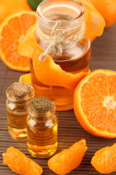 Olio essenziale di mandarino e mandarini su tappetino grigio di bambù — Foto Stock