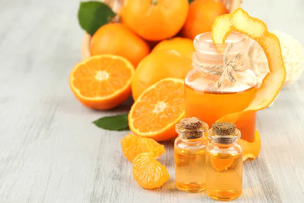 Tangerine essential oil and tangerines on wooden table — Stock Photo, Image