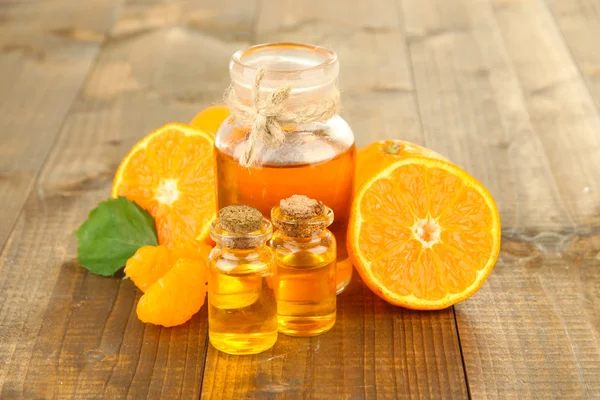 Tangerine essential oil and tangerines on wooden table — Stock Photo, Image