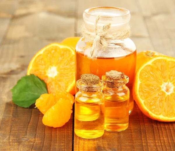 Tangerine essential oil and tangerines on wooden table — Stock Photo, Image