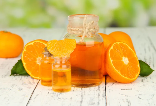 Tangerine essential oil and tangerines on wooden table, on nature background — Stock Photo, Image