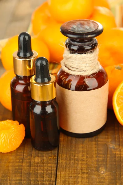 Tangerine essential oil and tangerines on wooden table — Stock Photo, Image