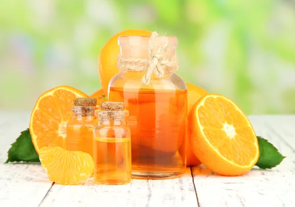 Tangerine essential oil and tangerines on wooden table, on nature background — Stock Photo, Image