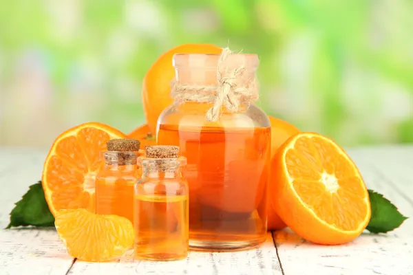 Tangerine essential oil and tangerines on wooden table, on nature background — Stock Photo, Image