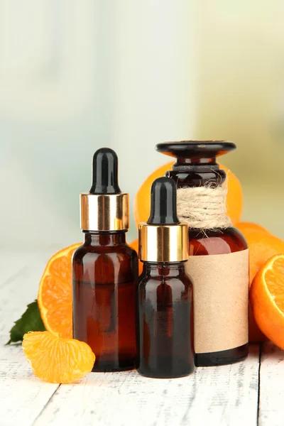 Aceite esencial de mandarina y mandarinas sobre mesa de madera —  Fotos de Stock