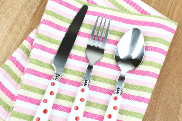 Kitchen cutlery on napkin on wooden table — Stock Photo, Image