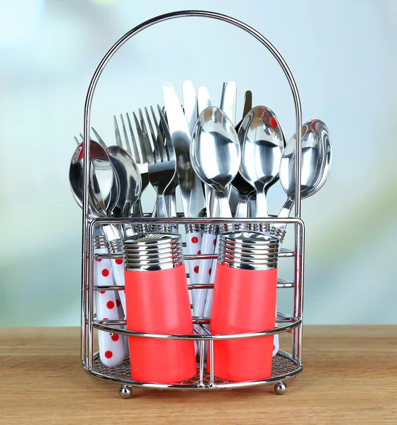 Couverts de cuisine en métal debout sur table en bois sur fond lumineux — Photo