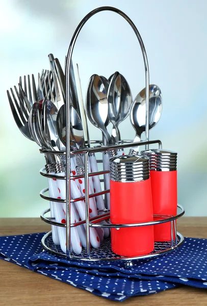 Cubertería de cocina en soporte de metal sobre mesa de madera sobre fondo brillante —  Fotos de Stock