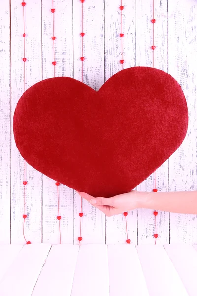 Hand holding big red heart on wooden background — Stock Photo, Image