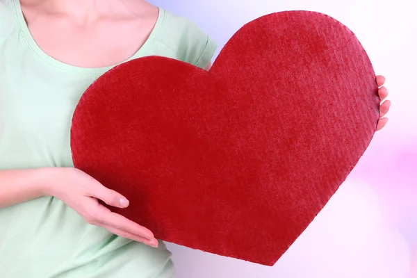 Mujer sosteniendo gran corazón rojo sobre fondo brillante —  Fotos de Stock