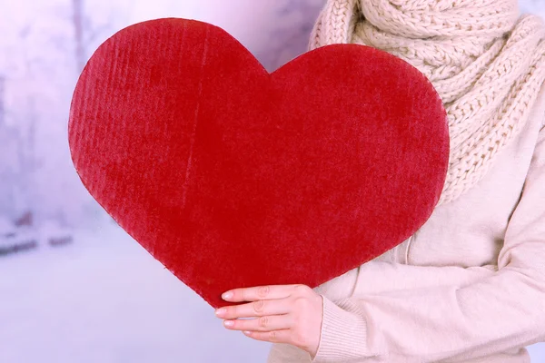 Mujer sosteniendo gran corazón rojo sobre fondo brillante —  Fotos de Stock