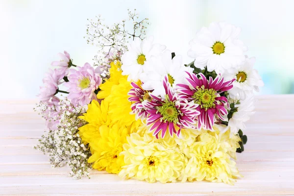 Schöne Chrysanthemenblüten auf dem Tisch auf hellem Hintergrund — Stockfoto