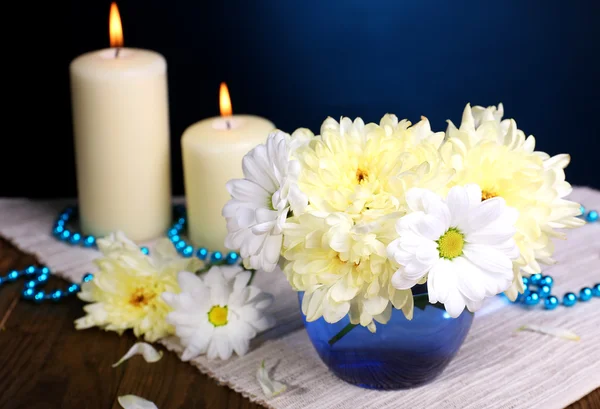 Beautiful chrysanthemum flowers in vase on table on dark blue background — Stock Photo, Image