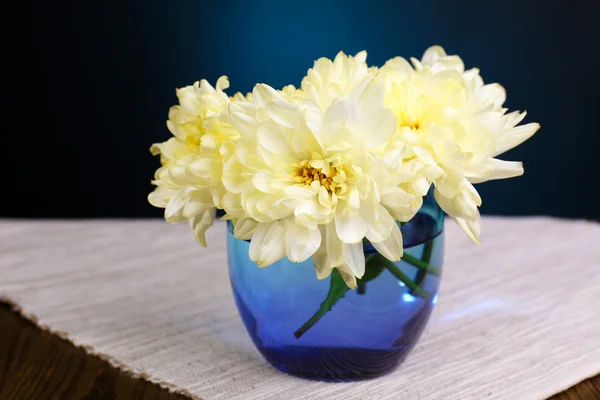 Mooie chrysant bloemen in vaas op tafel op donker blauwe achtergrond — Stockfoto
