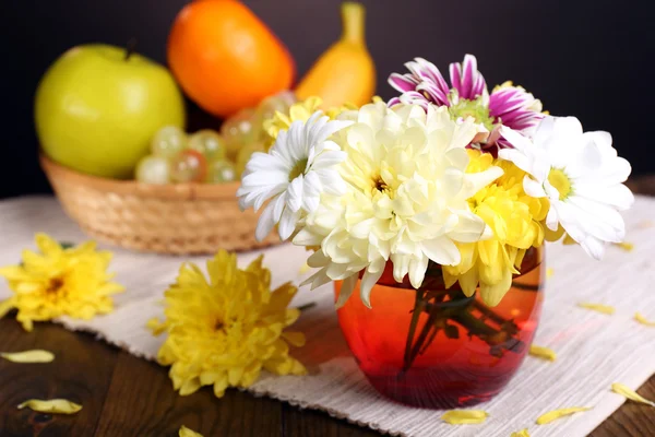 Schöne Chrysanthemenblüten in der Vase auf dem Tisch vor dunklem Hintergrund — Stockfoto