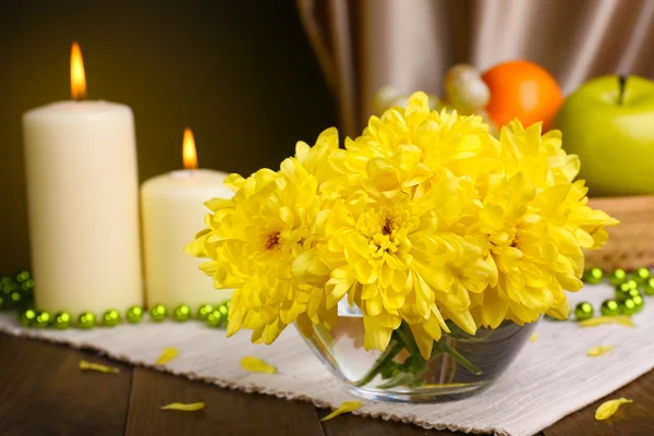 Mooie chrysant bloemen in vaas op tafel op donkere gele achtergrond — Stockfoto