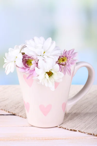 Piękne chryzantemowe kwiecie w kubek na stole na jasnym tle — Zdjęcie stockowe