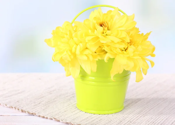 Hermosas flores de crisantemo en cubo en la mesa sobre fondo claro —  Fotos de Stock