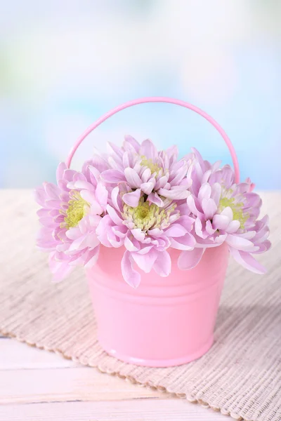 Lindas flores de crisântemo em balde na mesa no fundo claro — Fotografia de Stock
