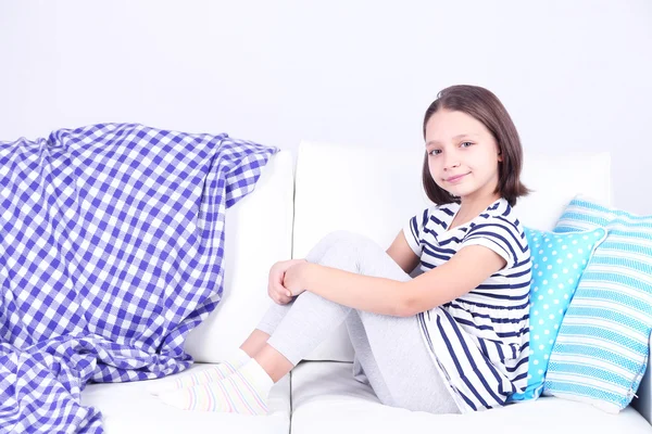 Menina bonita sentada no sofá, em casa fundo interior — Fotografia de Stock