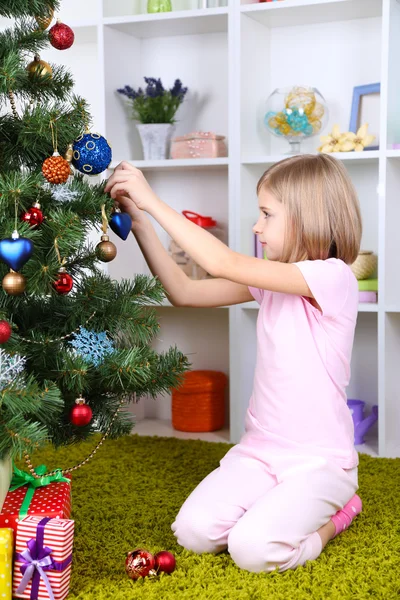 Klein meisje versieren kerstboom op kamer Stockfoto