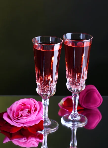 Composition with pink wine in glasses and roses on dark color background Stock Photo