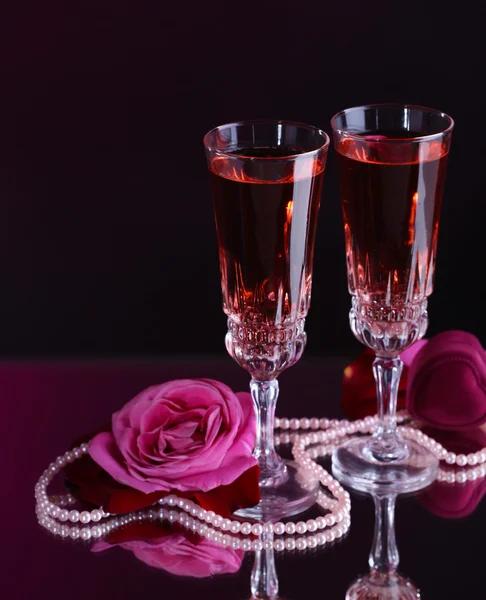 Composition with pink wine in glasses and roses on dark color background Stock Picture