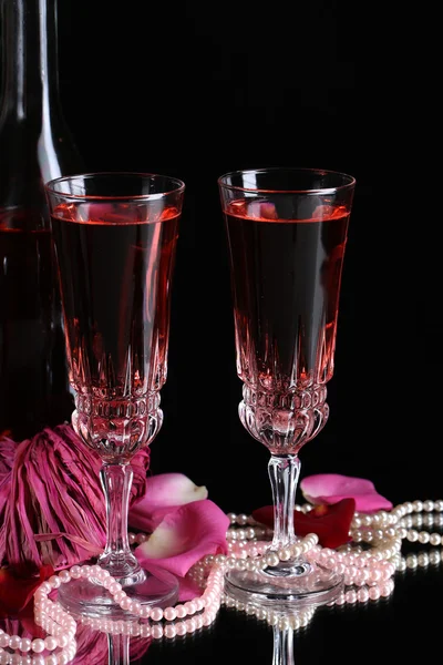 Composition with pink wine in glasses, bottle and roses isolated on black background Royalty Free Stock Images
