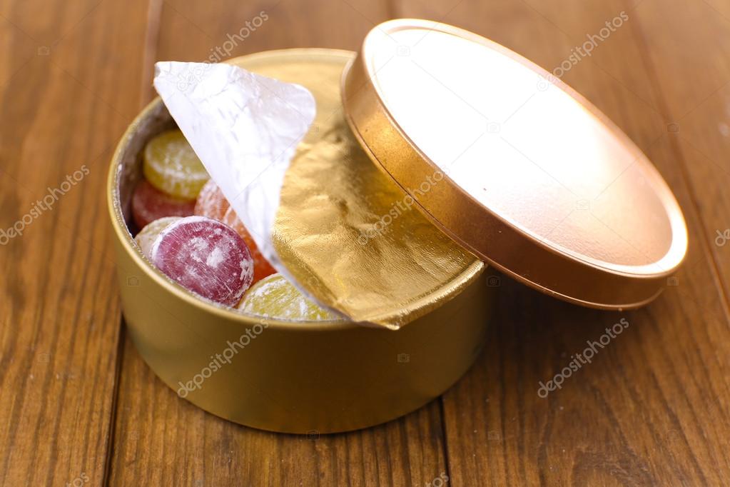 Sweet candies in metal can, on wooden background