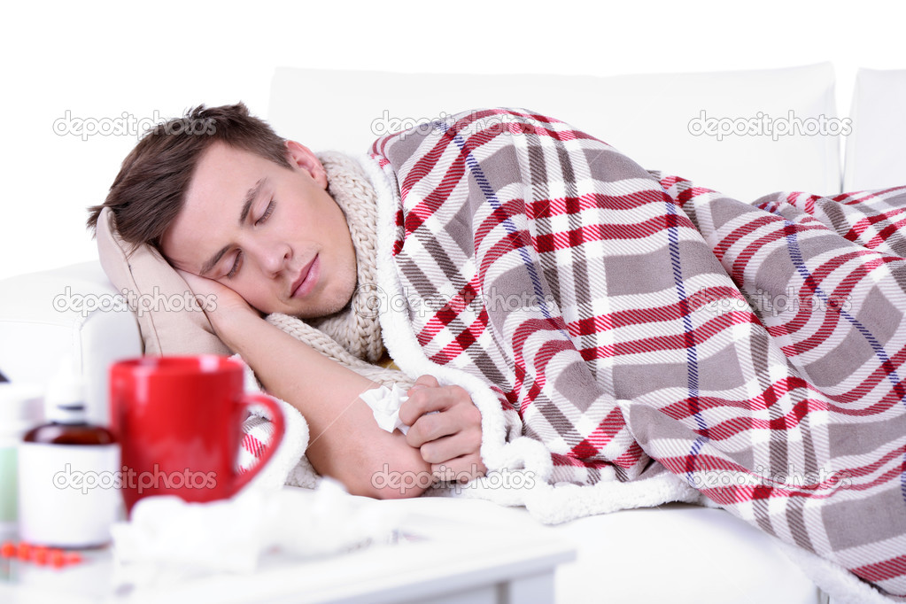 Guy wrapped in plaid lies on sofa is ill