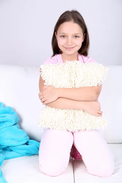 Beautiful little girl sitting on sofa, on home interior background — Stock Photo, Image