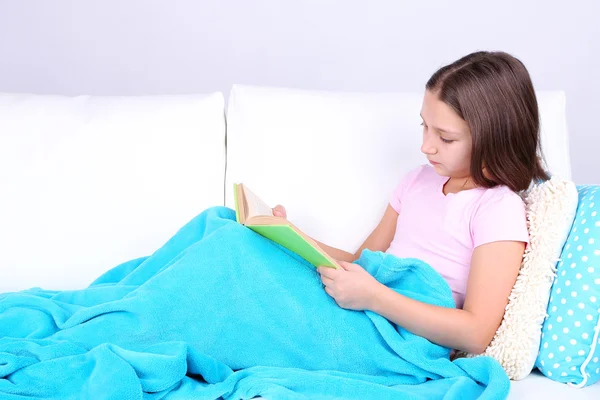 güzel küçük bir kız kanepe ile kitap, ev iç zemin üzerine oturan