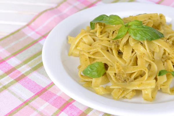 Läckra pasta med pesto på tallriken på bordet närbild — Stockfoto