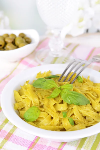 Läckra pasta med pesto på tallriken på bordet på ljus bakgrund — Stockfoto