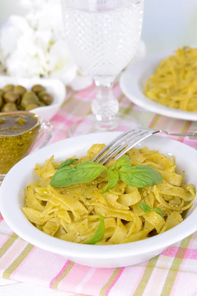 Heerlijke pasta met pesto op plaat op tafel op lichte achtergrond — Stockfoto