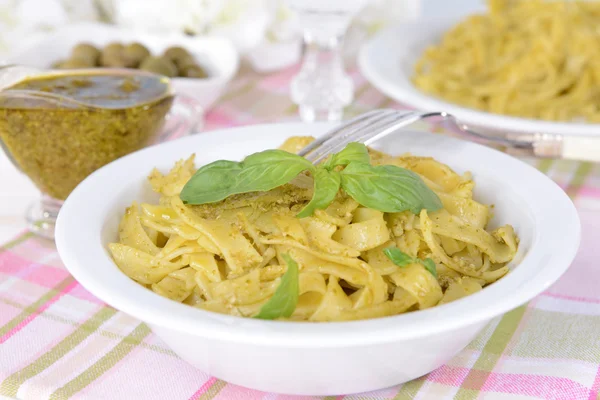 Delicioso macarrão com pesto na placa na mesa no fundo claro — Fotografia de Stock