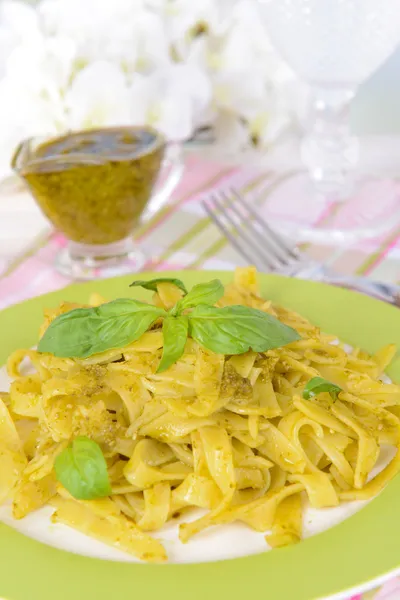 Heerlijke pasta met pesto op plaat op tafel op lichte achtergrond — Stockfoto