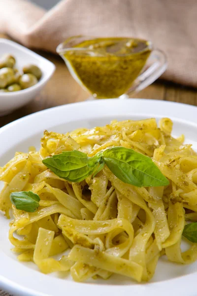 Massa deliciosa com pesto no prato na mesa close-up — Fotografia de Stock