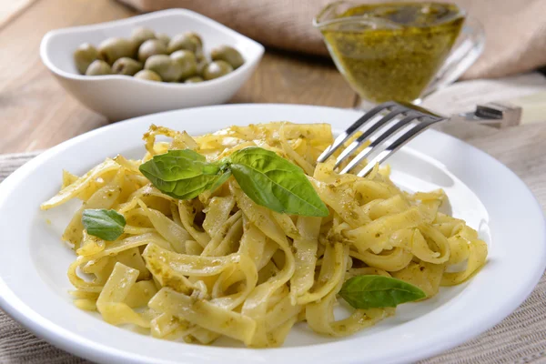 Läckra pasta med pesto på tallriken på bordet närbild — Stockfoto