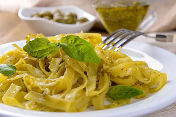 Massa deliciosa com pesto no prato na mesa close-up — Fotografia de Stock