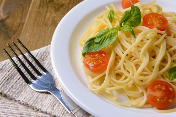 Delicious spaghetti with tomatoes on plate on table close-up — Stock Photo, Image