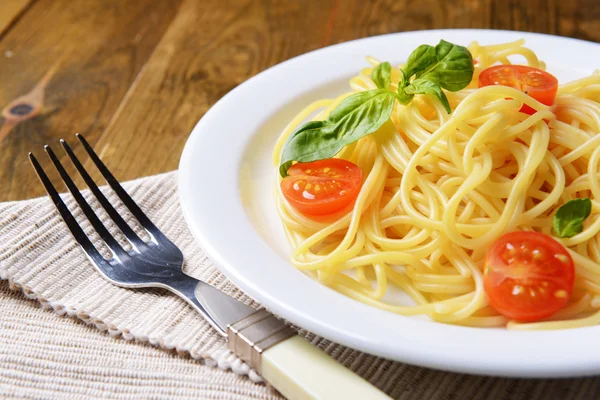 Utsökt spaghetti med tomater på tallriken på bordet närbild — Stockfoto