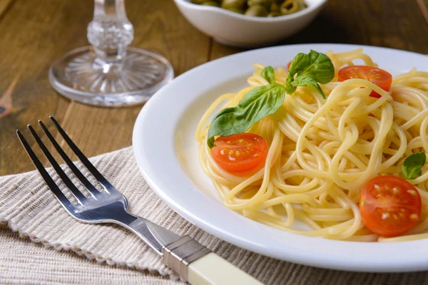 Deliciosos espaguetis con tomates en plato en la mesa de primer plano —  Fotos de Stock