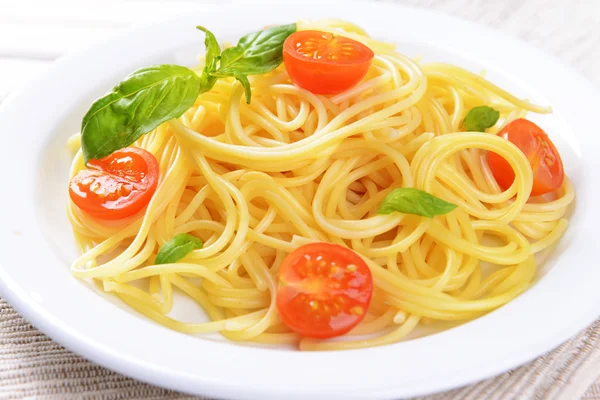 Delicious spaghetti with tomatoes on plate on table close-up — Stock Photo, Image
