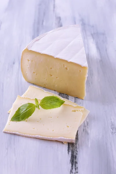 Tasty Camembert cheese with basil, on wooden table — Stock Photo, Image