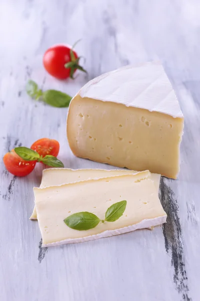 Sabroso queso Camembert con tomate y albahaca, sobre mesa de madera — Foto de Stock