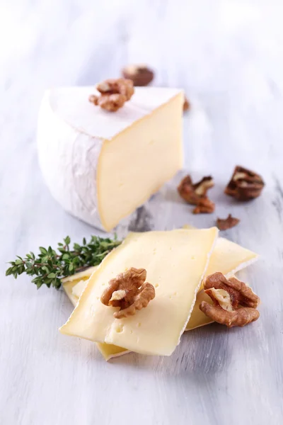Tasty Camembert cheese with nuts and thyme, on wooden table — Stock Photo, Image