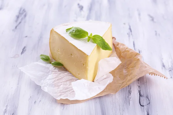 Smakelijke camembert kaas met basilicum, op houten tafel — Stockfoto