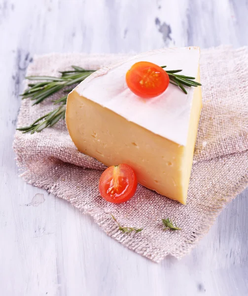Tasty Camembert cheese with rosemary and tomato, on wooden table — Stock Photo, Image