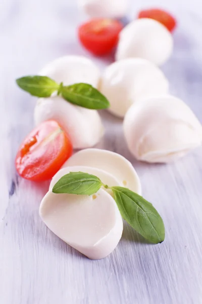 Ahşap masa üstünde domates ve fesleğen ile lezzetli mozzarella peyniri — Stok fotoğraf